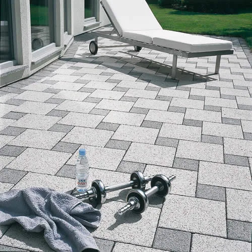 Terrasse mit hellem Plattenbelag und angrenzender Bepflanzung